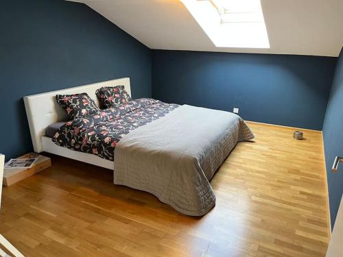 1 dormitorio con cama y pared azul en Sonnige Loft mit Terrasse, Ladestation für Elektrofahrzeuge en Schindellegi