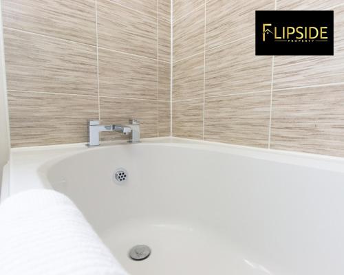 uma banheira na casa de banho com uma placa na parede em Contractors & Groups & Family Relocation - Flipside Property Aylesbury - Call Us Today For Special Offer! em Bierton