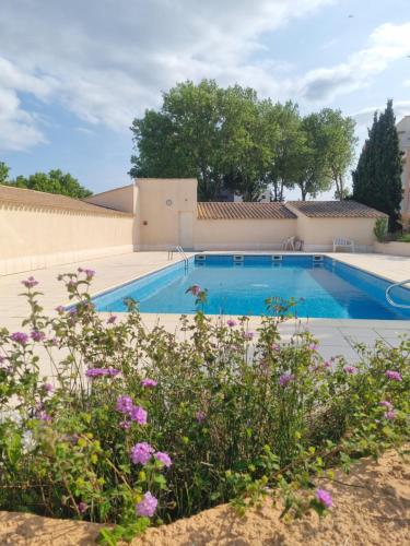 a swimming pool with flowers in the foreground at Cap Capistol Golf, appartement 2 chambres in Cap d'Agde