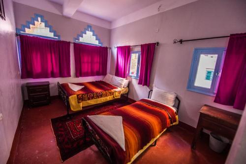 a bedroom with two beds and pink curtains at Etoile des Gorges in Aït Baha