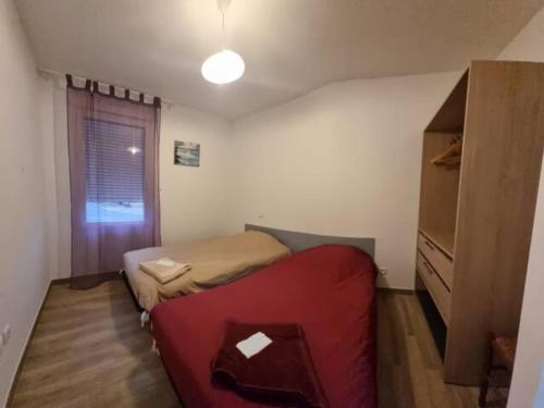 ein kleines Schlafzimmer mit einem roten Sofa und einem Fenster in der Unterkunft Maison neuve dans Saintes avec terrasse et jardin in Saintes