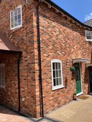 a brick building with a green door and windows at In the heart of the new forest in Fordingbridge
