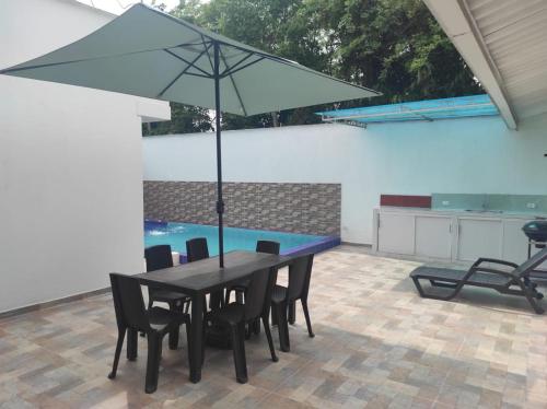 a table with chairs and an umbrella in a patio at Villas Campestres las Heliconias - Villa Ginger in Villavicencio