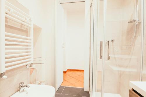 uma casa de banho branca com um chuveiro e um WC. em Ca' Letizia em Stresa