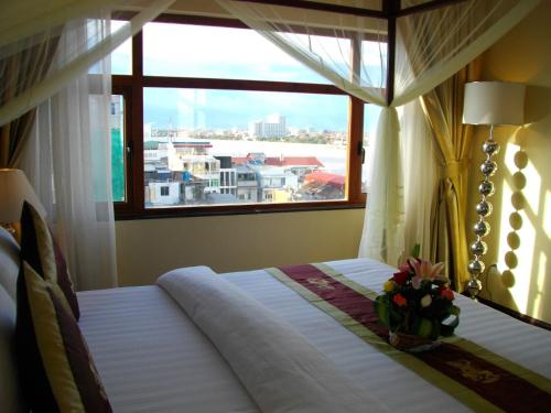 a bedroom with a bed with a large window at Lux Riverside Hotel & Apartment in Phnom Penh