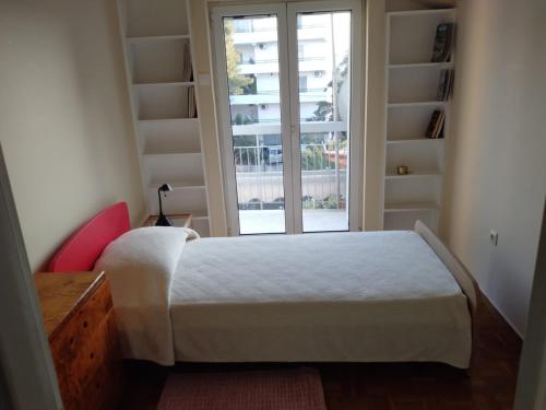 a bedroom with a bed and a large window at SUNNY APARTMENT NORTHERN ATHENS in Athens