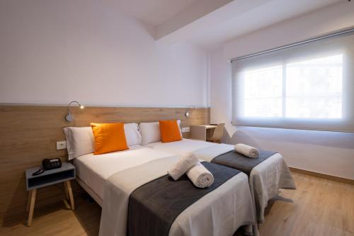 1 dormitorio con 1 cama blanca grande con almohadas de color naranja en Hostal Sans en Barcelona