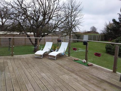 two white chairs sitting on a wooden deck at Leira in Saint-Aubin-dʼArquenay