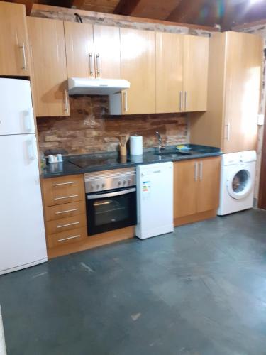 a kitchen with white appliances and wooden cabinets at O Busto Aldea Rural, Apartamento HORNO 2 in A Pobra do Brollon