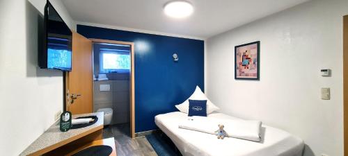 Habitación pequeña con cama y pared azul en Donau-Hotel, en Sinzing