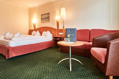 a hotel room with two beds and a couch at Ferienhotel Jörglerhof in Hainzenberg