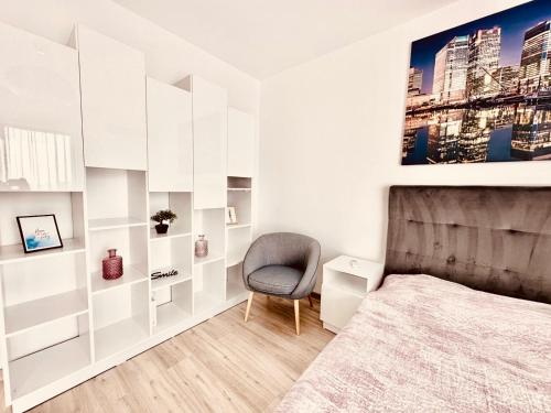 - une chambre aux murs blancs avec un lit et une chaise dans l'établissement At the TOP Plaza Studio, à Bucarest