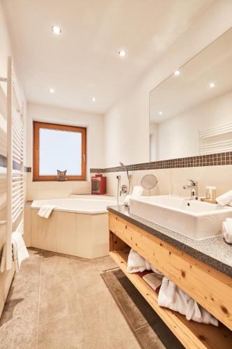a bathroom with a tub and a large mirror at Ferienhotel Jörglerhof in Hainzenberg
