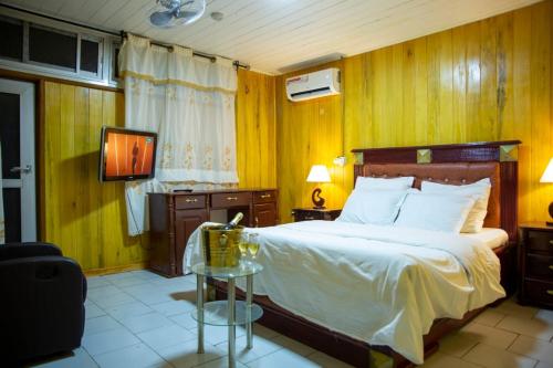 ein Schlafzimmer mit einem großen Bett und einem TV in der Unterkunft La Maison du Bonheur in Douala