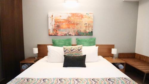 a bedroom with a white bed with a painting on the wall at 9311 Fabulous Resort in the Heart of Noosa in Noosa Heads