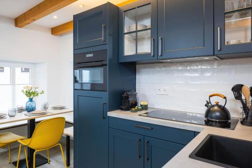 a kitchen with blue cabinets and a sink at Stadtmauer-Apartments - Stilvolle Wohnung mit King Bett direkt an der historischen Stadtmauer in Nördlingen