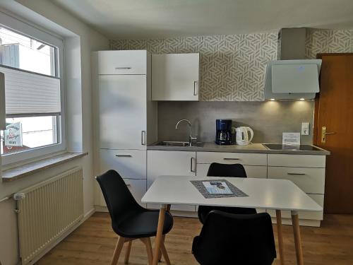eine Küche mit einem Tisch, Stühlen und einem Waschbecken in der Unterkunft Haus Elisa in Helgoland