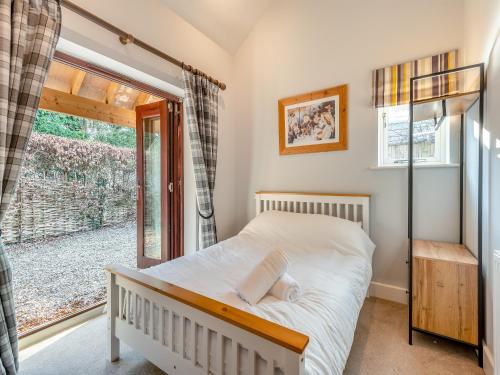 a bedroom with a bed and a large window at The Cow Shed in Farnham