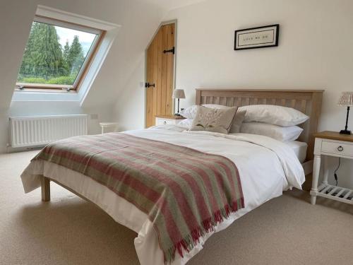 a white bedroom with a large bed and a window at Meadow Cottage in Hampshire's Test Valley in Andover