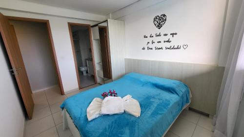 um quarto com uma cama azul e 2 toalhas em Boutique Ecolife em Porto de Galinhas