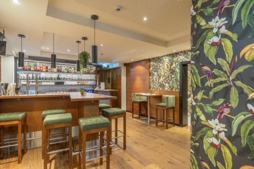 a restaurant with a bar with green stools at Ferienhotel Jörglerhof in Hainzenberg