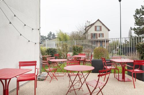a group of tables and chairs with red tables at ibis Styles Versailles Saint Quentin en Yvelines in Saint-Cyr-lʼÉcole