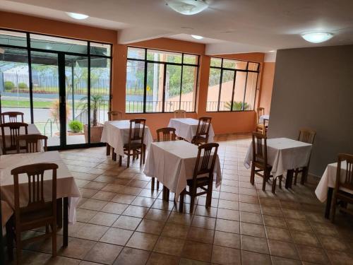 una sala da pranzo con tavoli, sedie e finestre di Vicz Palace Hotel a Curitiba
