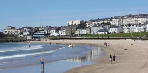 a group of people walking on the beach at Portrush by the Sea - 6 Golf Terrace in Portrush