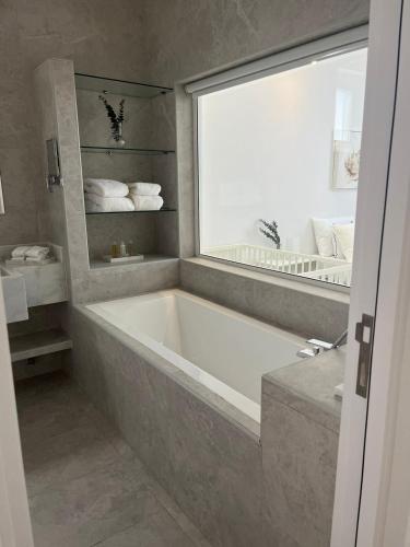 ein Bad mit einer Badewanne und einem Fenster in der Unterkunft غيمة مصفوت 