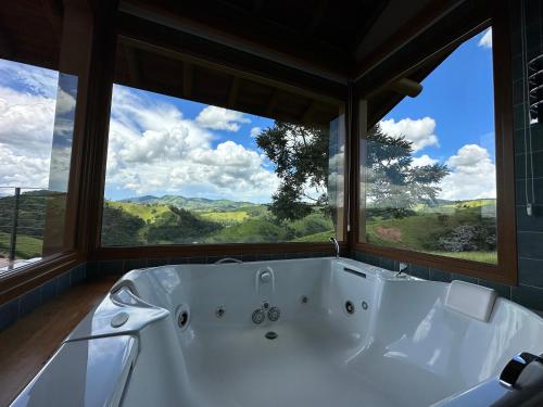 a bath tub in a room with a large window at Lavandas de Cunha Pousada Boutique in Cunha