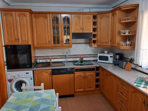 uma cozinha com armários de madeira, um lavatório e uma máquina de lavar louça em Casa Rosangela em Almonacid de Toledo