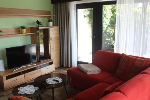 a living room with a red couch and a television at Komfort-Ferienwohnung Auf der Eulenburg in Grafengehaig