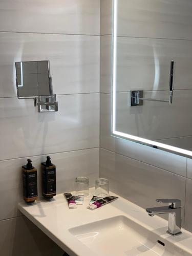 a white bathroom with a sink and a mirror at Mercure Hotel Riesa Dresden Elbland in Riesa