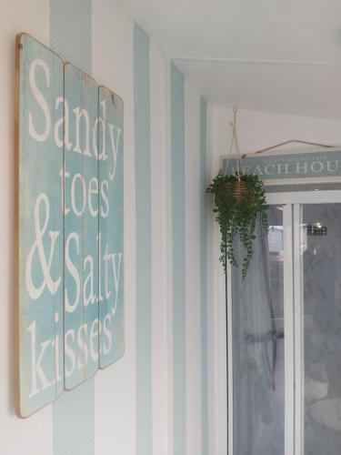 una ventana con un letrero que lee dedos arenosos y besos salados en Jock's Place en Whitley Bay