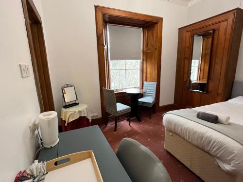 a bedroom with a bed and a desk and a table at Columba House in Kingussie
