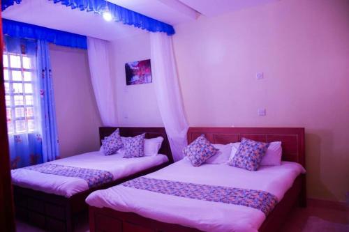 Lake View EstateにあるSerenity Homeのピンクとブルーの枕が備わる客室内のベッド2台