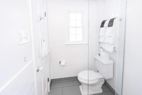 a white bathroom with a toilet and a window at Canalside Inn in Rehoboth Beach