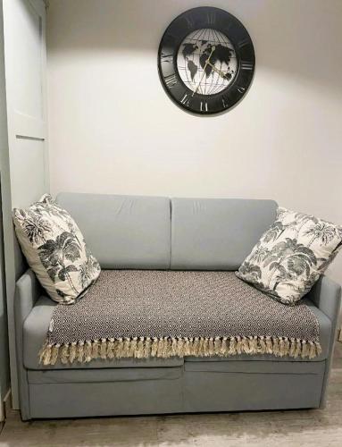 - un canapé dans une chambre avec une horloge murale dans l'établissement Le Studio Welfare, à Amiens