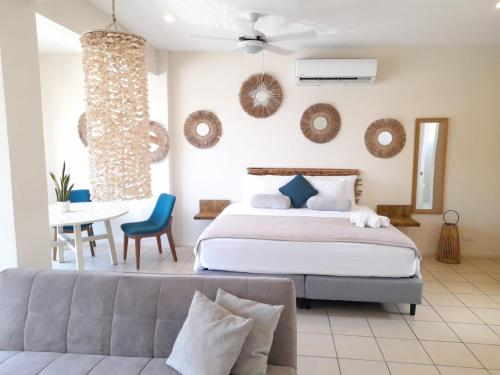 a bedroom with a bed and a couch and a table at Zulu Surf Hotel Tamarindo in Tamarindo