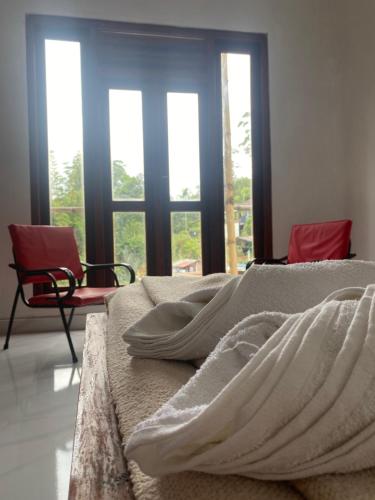 a bedroom with a bed and a chair and windows at Misty Bliss in Ella