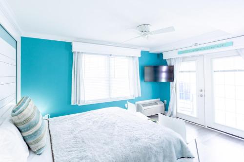 a blue bedroom with a bed and two windows at Canalside Inn in Rehoboth Beach