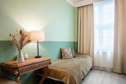 a bedroom with a bed and a table with a lamp at Hotel Nieuw Antiek in Helden