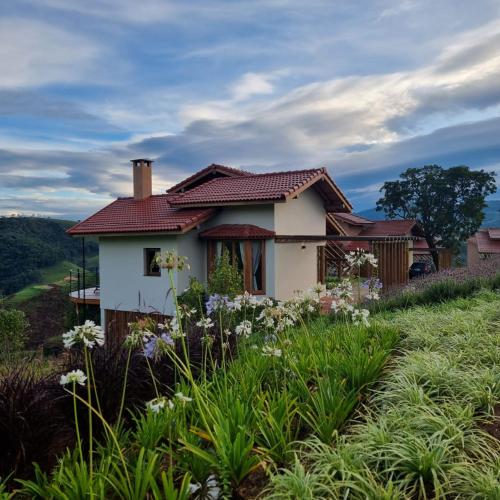 a house on top of a hill with flowers at Lavandas de Cunha Pousada Boutique in Cunha