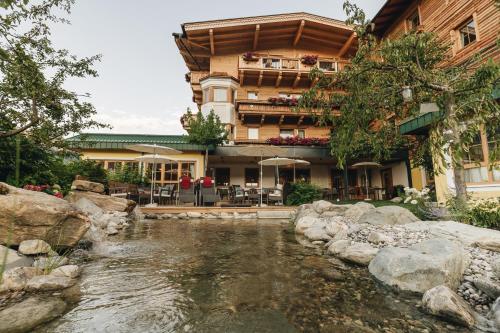 a hotel with a river in front of a building at Ferienhotel Jörglerhof in Hainzenberg