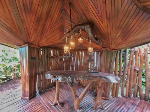 uma mesa de madeira num alpendre com tecto de madeira em The Corbin Guest House em Fehendhoo
