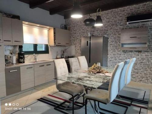 a kitchen with a glass table and white chairs at Dimitra's Villa in Evia, Greece in Loukísia