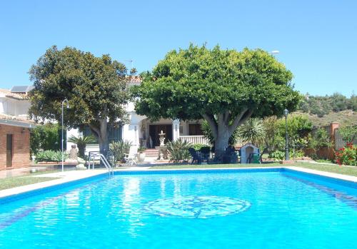 una gran piscina azul en un patio con árboles en Villa Maria Teresa, en Benajarafe