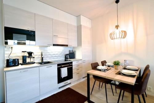 une cuisine avec des placards blancs et une table avec des chaises dans l'établissement Brandnew Modern Condo with Sauna, à Rovaniemi