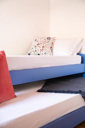 a bunk bed with blue and white sheets and a red pillow at IseoLakeRental - Casa del Pescatore in Riva di Solto