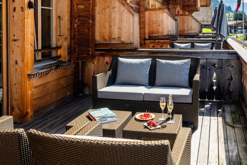 a patio with a couch and a table and chairs at Hotel-Restaurant Valrose in Gstaad